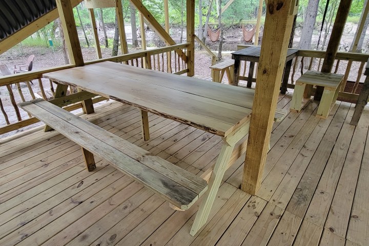 Wooden picnic table under rustic shelter on wooden deck.