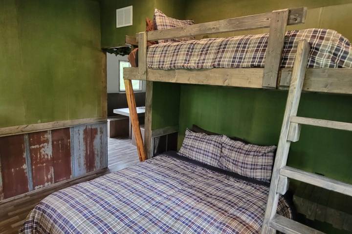 Room with wooden bunk beds, plaid bedding, and green walls.