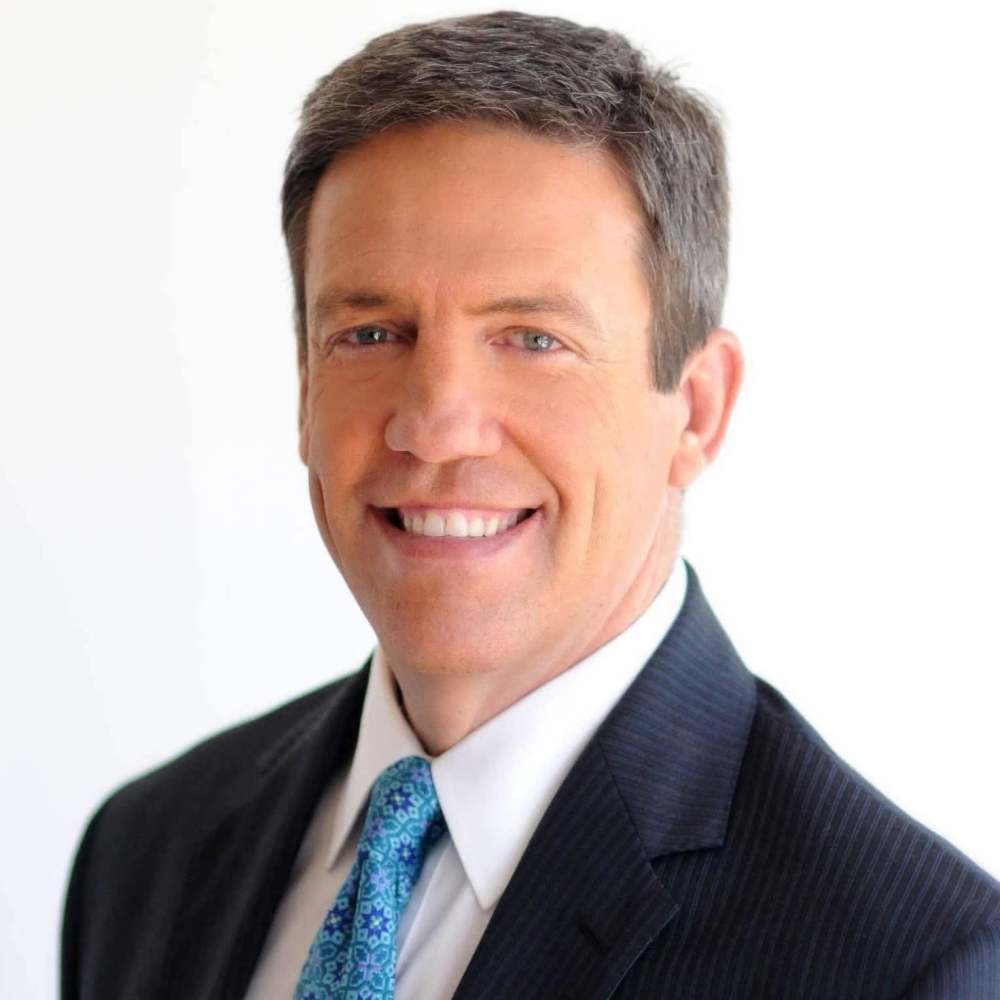 Ed Piotrowski Smiling man in suit with light blue tie, white background.